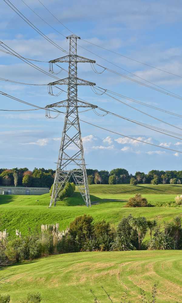 vertical-shot-high-voltage-electric-tower-with-green-meadow-